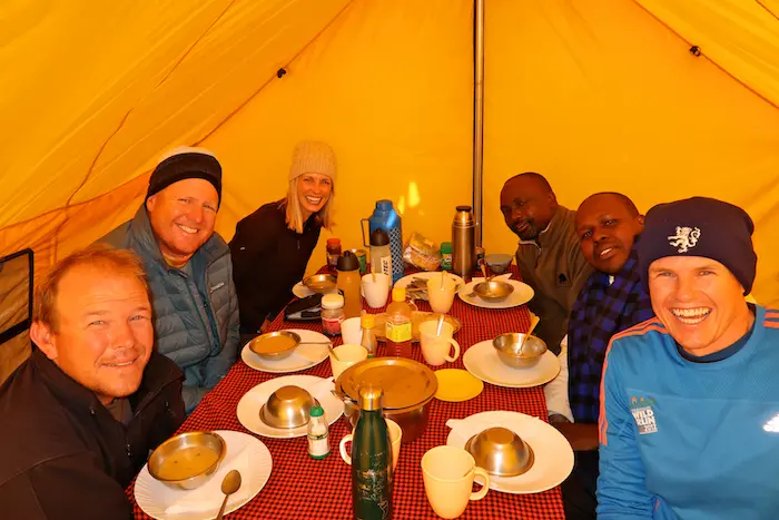 Trekkers enjoying drinks inside the mess tent during 7-day kilimanjaro group join trek - machame route